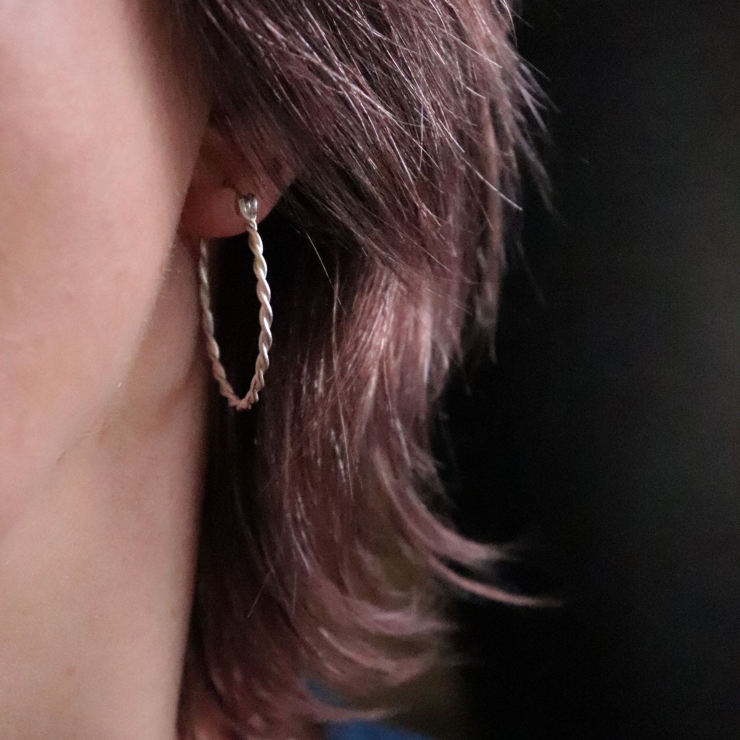 Close-up of an earring worn by a person with a dark background