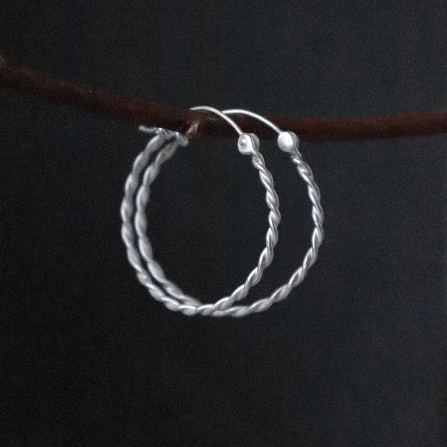 Twisted Silver hoop earrings on a dark background