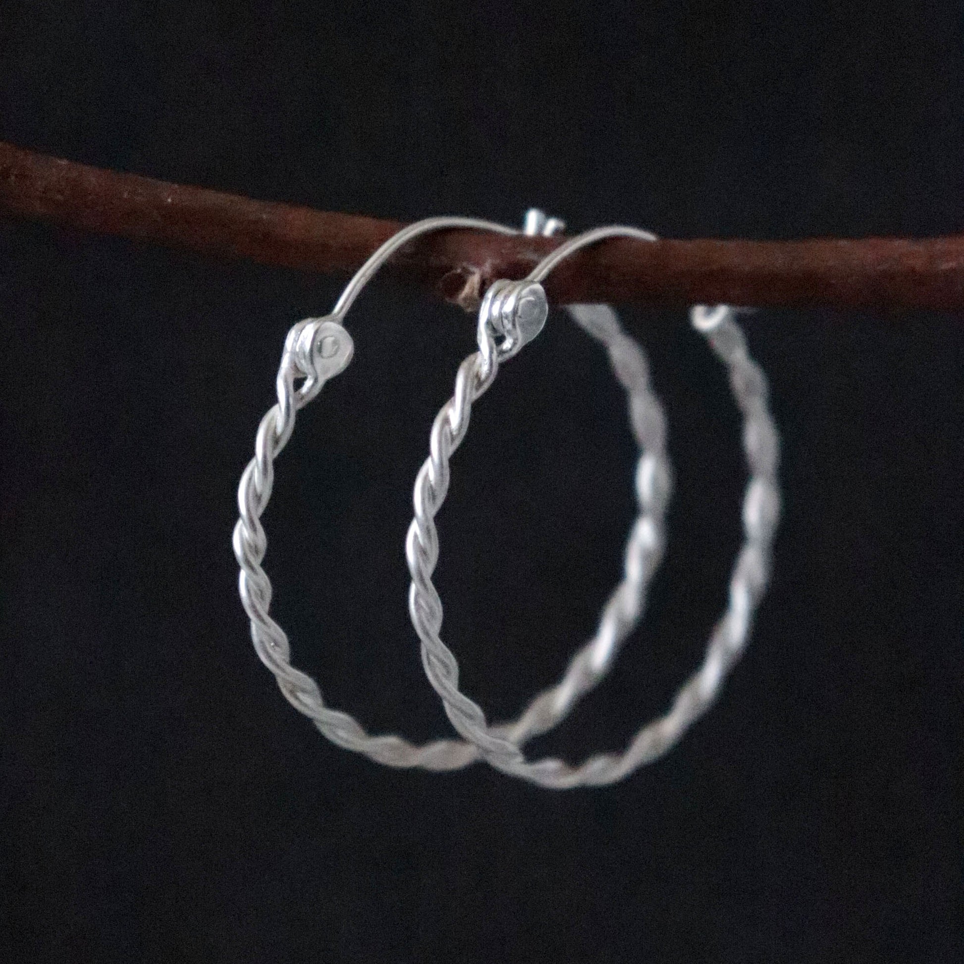 Twisted Silver hoop earrings on a dark background