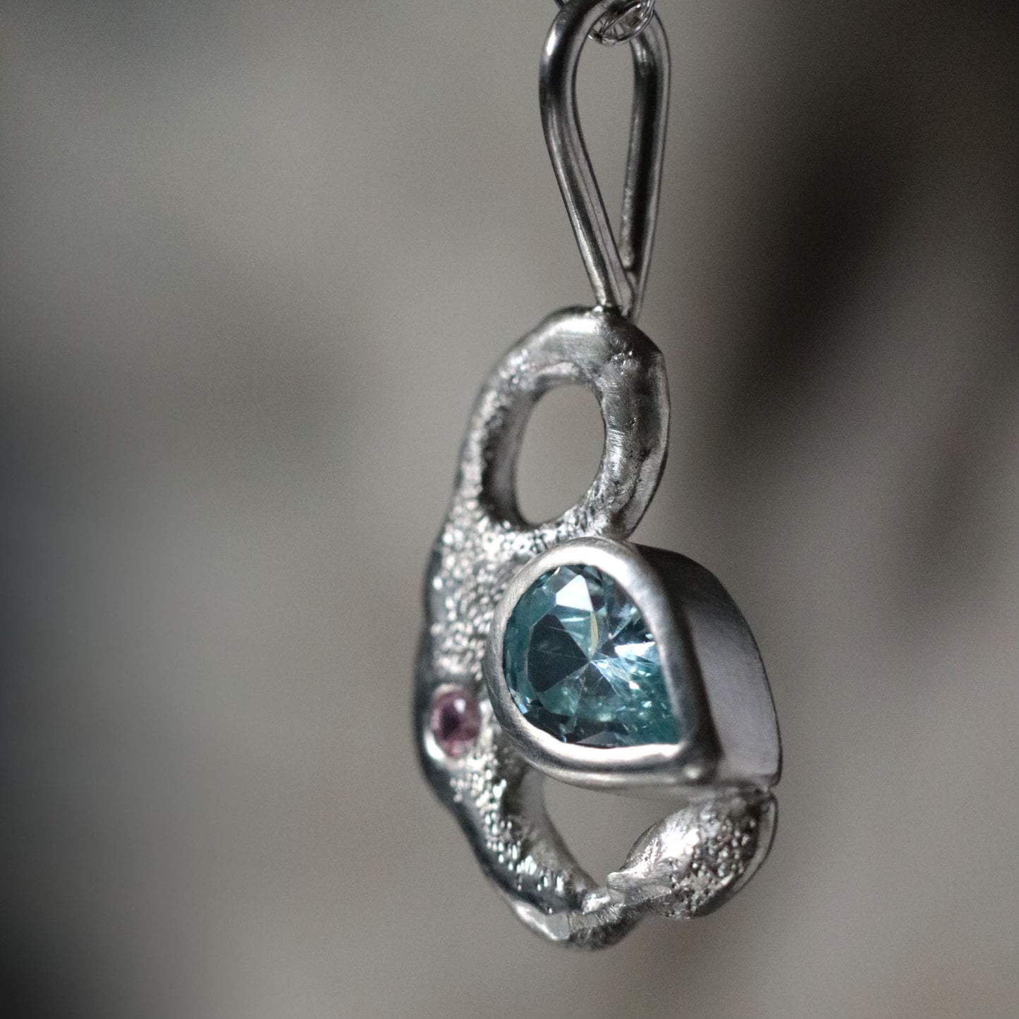 Silver pendant with a blue gemstone on a blurred background