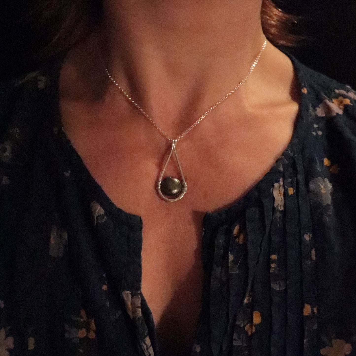 Necklace with a pendant worn by a person against a dark background