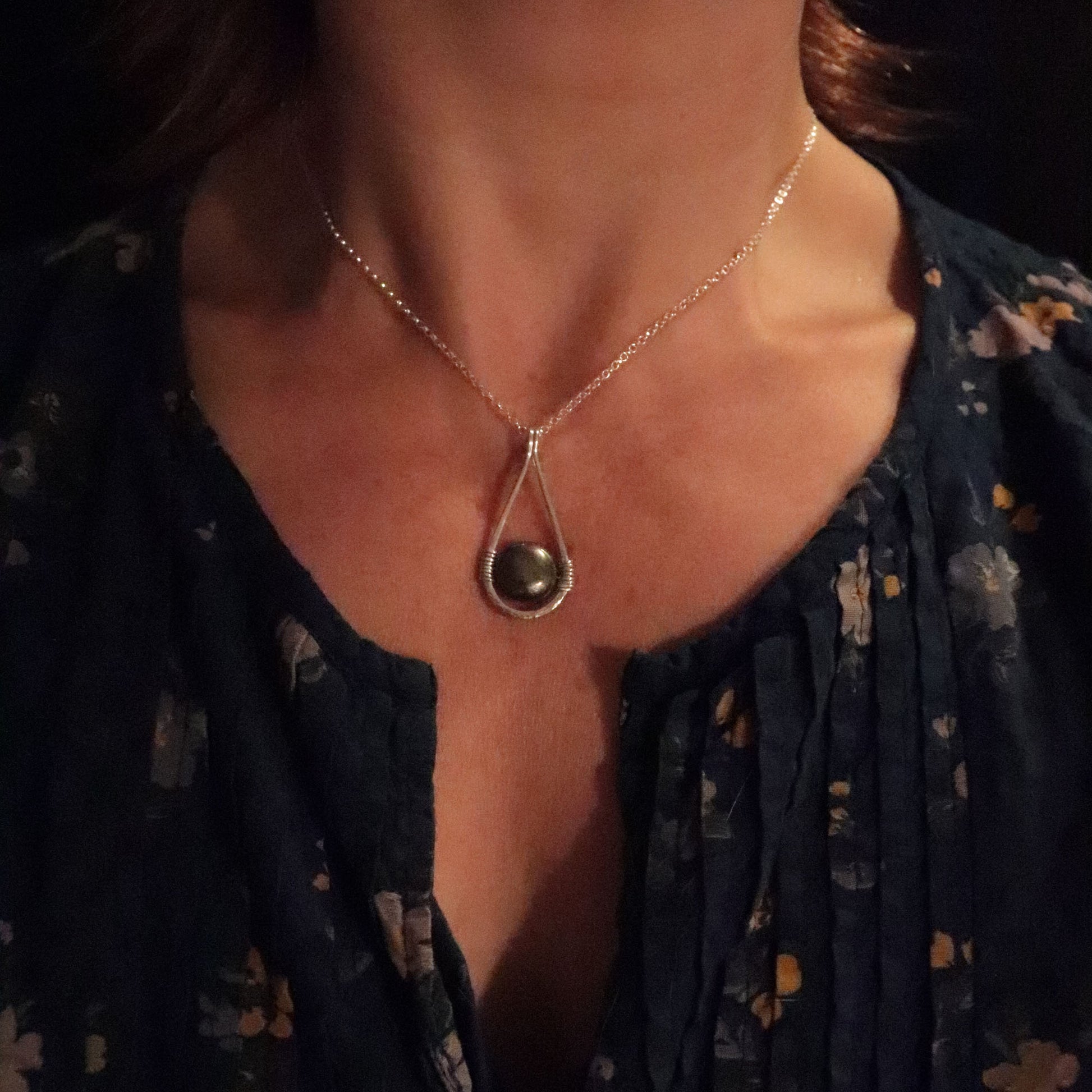Necklace with a pendant worn by a person against a dark background
